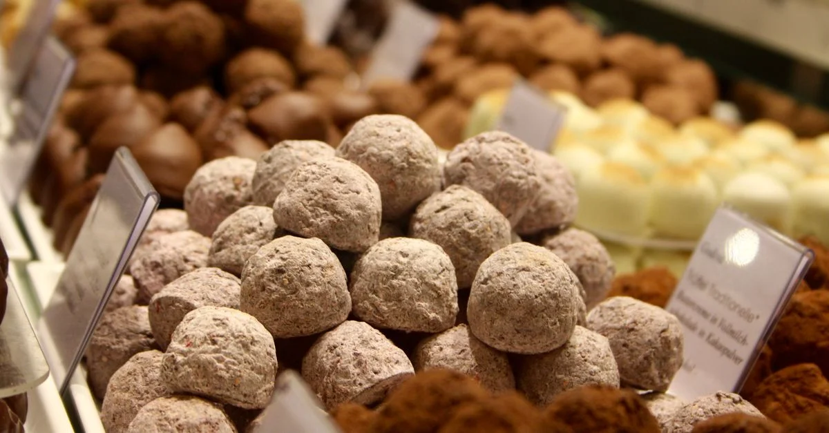 Une variété de délicieuses truffes en chocolat en exposition dans une confiserie avec étiquettes.