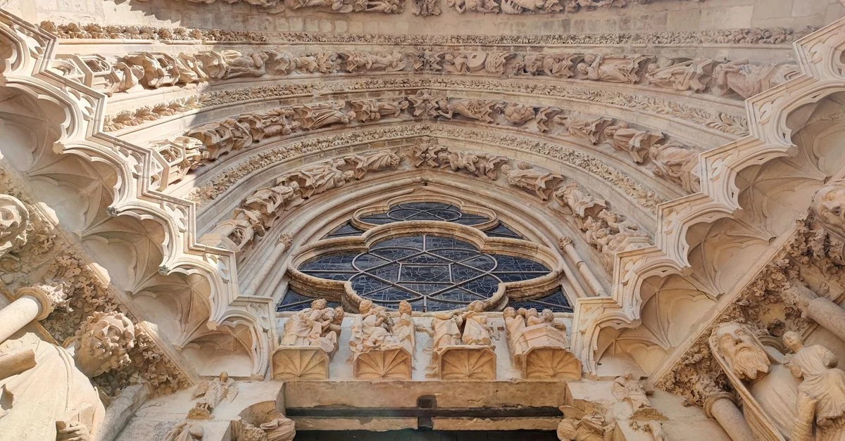 Vue rapprochée de l'entrée gothique de la cathédrale de Reims avec des sculptures en pierre détaillées et une rosace.