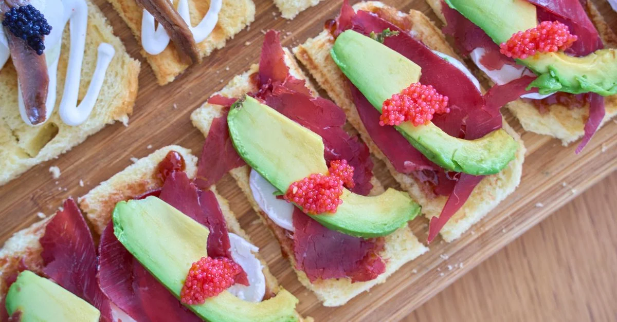 Des tapas appétissantes avec avocat, jambon serrano et œufs de poisson sur du pain croustillant.