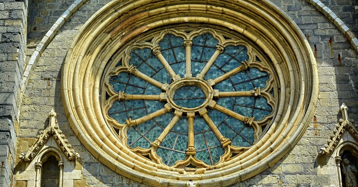 Gros plan d'un détail de rosace gothique sur la façade d'une ancienne cathédrale en pierre.