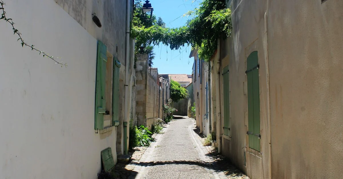 Une ruelle pittoresque dans une ville européenne historique avec des chemins en pierre au soleil et une architecture charmante.