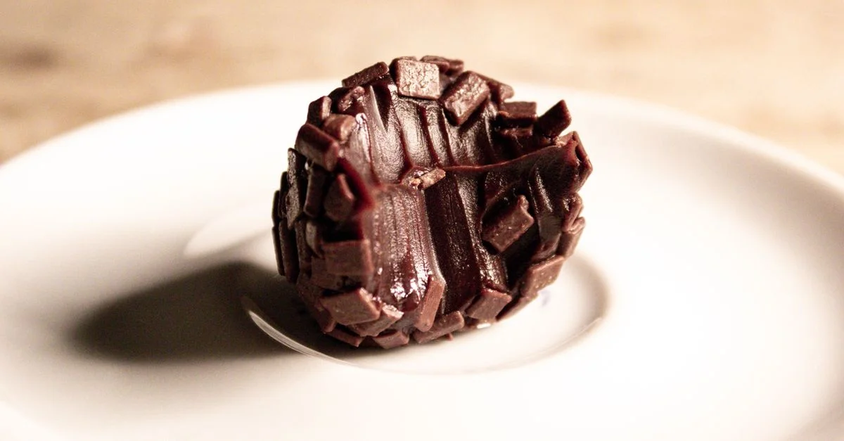 Truffe en chocolat élégante présentée artistiquement sur une soucoupe blanche sleek, parfaite pour les amateurs de desserts.