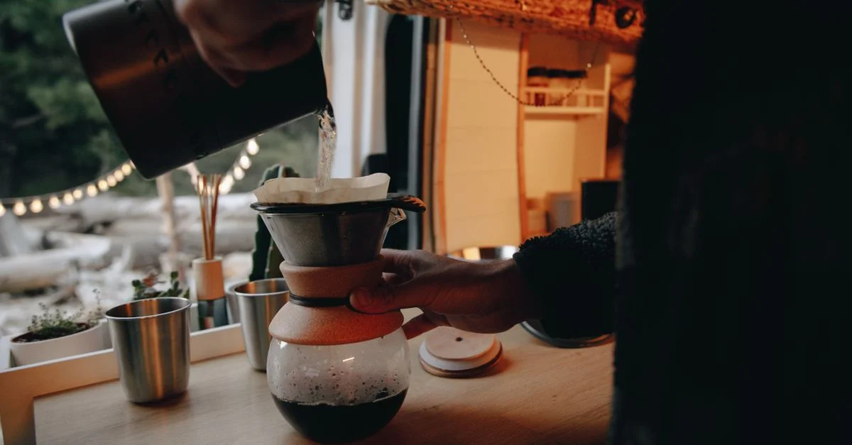 Un moment chaleureux et intime de préparation de café filtre à l'intérieur d'un camping-car confortable.